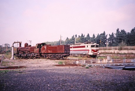 A rusting steam locomotive and an electric locomotive stand off to the side in the yard in Mulhouse, Alsace, France, on October 20, 2000. Photograph by Fred M. Springer, © 2014, Center for Railroad Photography and Art. Springer-Swiss(2)-01-26