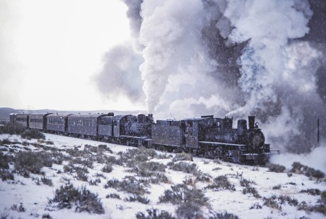 Viejo Expreso Patagónico (Old Patagonian Express) steam locomotives 6 and 15 lead a passenger train in the snow-covered Andes mountain range in Cerro Mesa, Río Negro, Argentina, on October 14, 1991. Photograph by Fred M. Springer, © 2014, Center for Railroad Photography and Art, Springer-PA-BR-SOAM-ME-ARG2-23-23