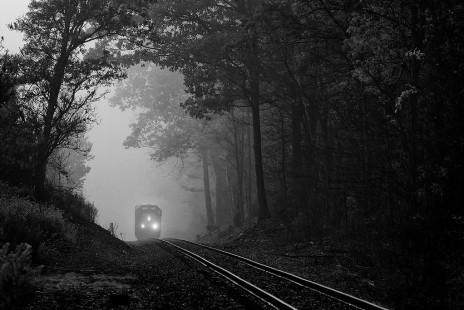 A CSX local emerging from fog and seemingly approaching a bleak darkness is using the last remaining active route of the New York, Ontario and Western Railway, Seneca Hill, NY.
