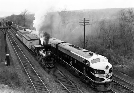 This image features two Erie Railroad centennial trains: steam locomotive no. 25 alongside F-unit diesel locomotive no. 711. The photograph was shot from the Route 17 overpass as the trains headed east toward Jersey City, New Jersey. Shot on April 4, 1951, this scene marked the 100th anniversary of the completion of the Erie's original route linking the Hudson River and Lake Erie. Photograph by Donald W. Furler. Furler-19-067-02, © 2017, Center for Railroad Photography and Art