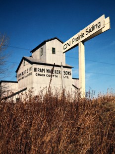 Station sign and grain elevator along the Canadian National Railway in Prairie Siding, Ontario, on November 23, 1974. Photograph by John F. Bjorklund, © 2015, Center for Railroad Photography and Art. Bjorklund-20-02-19