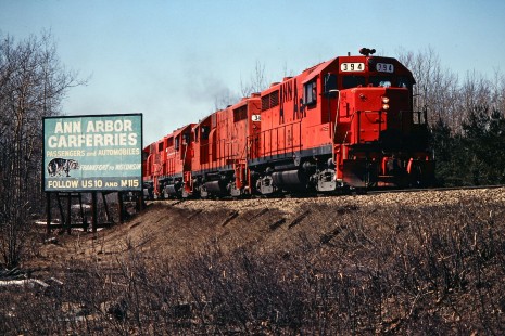 Southbound Ann Arbor Railroad freight train passing a billboard for the railroad's ferry service in Farwell, Michigan, on March 27, 1982. Photograph by John F. Bjorklund, © 2015, Center for Railroad Photography and Art. Bjorklund-03-27-16