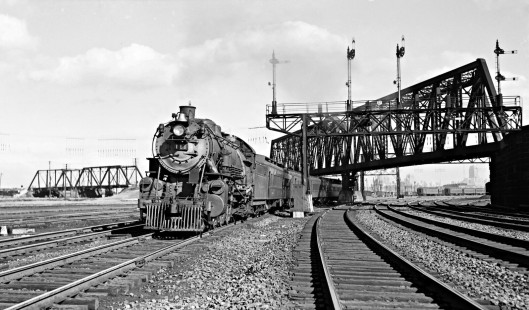 Reading Company 4-6-2 steam locmotive no. 111 pulling westbound passenger train no. 1613, the "Philadelphia Express," under the Lehigh Valley bridge near the Communipaw Avenue station at Jersey City, New Jersey, on October 28, 1939. The Manhattan skyline is visible in the distance under the bridge. Photograph by Donald W. Furler, © 2017, Center for Railroad Photography and Art, Furler-08-039-01