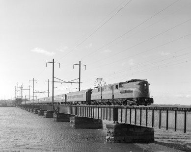 Penn Central GG1 electric locomotive no. 4877, a restored locomotive, leads an eastbound passenger train over the Raritan Bay Drawbridge in Perth Amboy, New Jersey, on October 29, 1983. Photograph by Victor Hand. Hand-NYC-PC-CR-31-0858