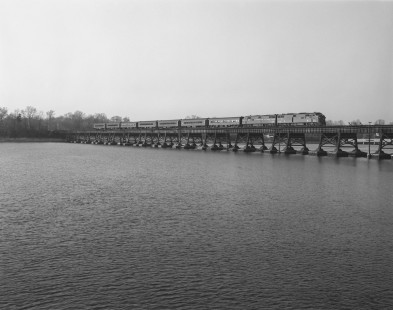 Penn Central diesel locomotive no. 4209, still wearing the paint of predecessor Pennsylvania Railroad, crosses the Navesink River with southbound passenger train no. 1111 in Red Bank, New Jersey, on April 17, 1968. Photograph by Victor Hand. Hand-PRR-32-088.