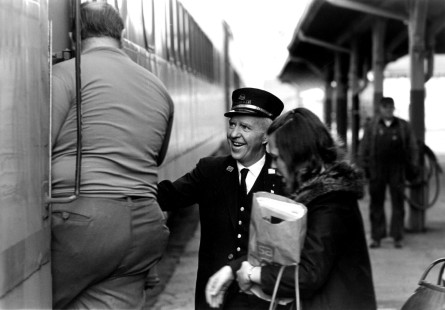 Conductor Tom Burke smiles as he helps passengers climb aboard the last Milwaukee Road passenger train out of the Madison, Wisconsin depot on April 30, 1971.