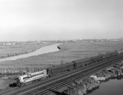 Erie Lackwanna Railway diesel locomotive no. 914 leads a passenger train near Rutherford, New Jersey, on August 15, 1968. The Manhattan skyline and the Empire State Building are visible in the distance. Photograph by Victor Hand; Hand-EL-30-151
