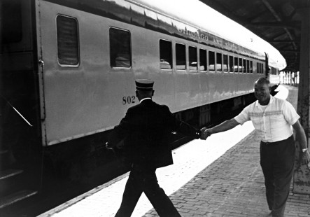 A conductor and ticket agent shake hands in a farewell gesture as the last Chicago & North Western "400" passenger train prepares to head west out of Madison, Wisconsin, in 1963.