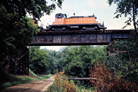 Eastbound Milwaukee Road freight train led by SW1 switcher on bridge near Isinours, Minnesota, on July 19, 1976. Photograph by John F. Bjorklund, © 2016, Center for Railroad Photography and Art. Bjorklund-65-06-13