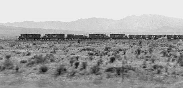 Distant view from moving vehicle imparts motion to eastbound Southern Pacific Railroad freight train of hoppers approaching Marathon, Texas, in April 1985. Photograph by J. Parker Lamb, © 2017, Center for Railroad Photography and Art. Lamb-02-083-12
