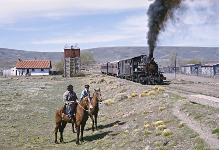 Two men on horseback greet the Old Patagonian Express (known locally as La Trochita) as it arrives at the remote station of Fitalancao, near the halfway point of the 250-mile line, on October 29, 1995. Photograph by Fred M. Springer, © 2016, Center for Railroad Photography and Art. Springer-CHI-ARG1-09-13