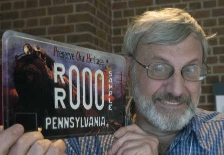 Dan Cupper with a Pennsylvania license plate featuring a Grif Teller painting. Center for Railroad Photography and Art. Photograph by Henry A. Koshollek