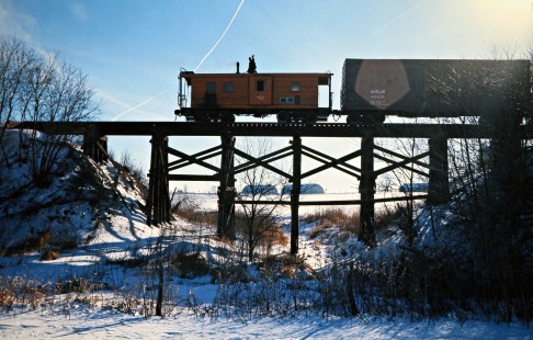 Caboose of a southbound Milwaukee Road freight train on bridge in Welland, Illinois, on January 22, 1977. Photograph by John F. Bjorklund, © 2016, Center for Railroad Photography and Art. Bjorklund-65-12-17