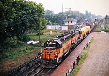 Westbound Milwaukee Road freight train crossing the Elgin, Joliet and Eastern at Rondout, Illinois, on July 6, 1975. Photograph by John F. Bjorklund, © 2016, Center for Railroad Photography and Art. Bjorklund-64-29-06
