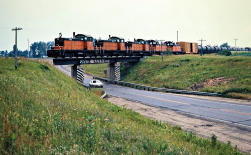 Eastbound Milwaukee Road freight train over bridge in Grand Meadow, Minnesota, on July 19, 1976. Photograph by John F. Bjorklund, © 2016, Center for Railroad Photography and Art. Bjorklund-65-04-13
