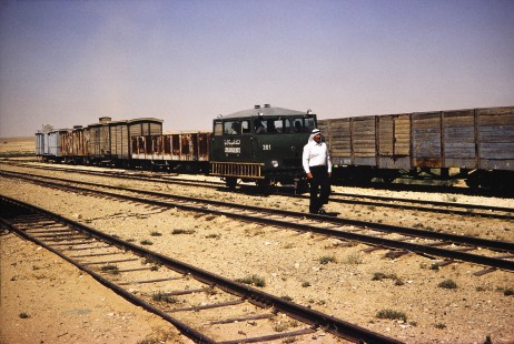Hedjaz Jordan Railway and Syrian Railways service train car no. 301 moves alongside a worker and several freight cars in Petra, Ma'an, Jordan, on July 18, 1991. Photograph by Fred M. Springer, © 2014, Center for Railroad Photography and Art. Springer-Hedjaz-ZimZam(1)-06-25