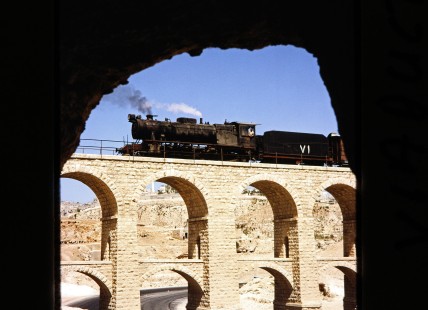 Hedjaz Jordan Railway 2-8-2 steam locomotive no. 71 seen through a cave as it travels over an aqueduct bridge in Amman, Jordan, on July 15, 1991. Photograph by Fred M. Springer, © 2014, Center for Railroad Photography and Art. Springer-Hedjaz-ZimZam(1)-02-16
