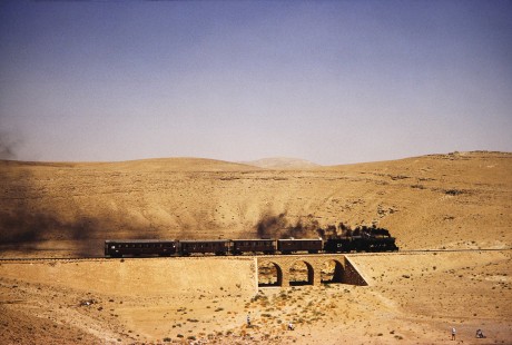 Hedjaz Jordan Railway and Syrian Railways 2-8-2 steam locomotive no. 51 moves across a short bridge in Petra, Ma'an, Jordan, on July 18, 1991. Photograph by Fred M. Springer, © 2014, Center for Railroad Photography and Art. Springer-Hedjaz-ZimZam(1)-06-28