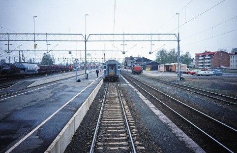 Swedish State Railways diesel locomotive moves forward on the tracks as both a passenger and a conductor look to board and depart the busy train station in Boden, Norrbotten, Sweden, on June 1, 1996. Photograph by Fred M. Springer, © 2014, Center for Railroad Photography and Art. Springer-So.Africa-NOR-SWE-15-09