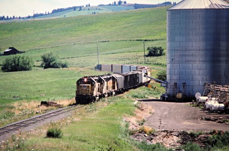 Westbound Camas Prairie Railroad freight train, owned and operated by Burlington Northern Railroad and Union Pacific Railroad, at Ferdinand, Idaho, on July 1, 1988. Photograph by John F. Bjorklund, © 2016, Center for Railroad Photography and Art. Bjorklund-93-19-02
