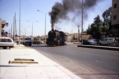 Hedjaz Jordan Railway 2-8-2 steam locomotive no. 51 crosses a high traffic street in Amman, Jordan, on July 17, 1991. Photograph by Fred M. Springer, © 2014, Center for Railroad Photography and Art. Springer-Hedjaz-ZimZam(1)-05-11