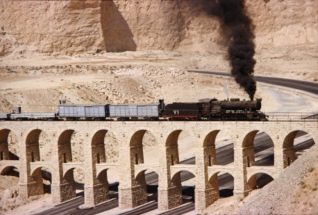 Hedjaz Jordan Railway 2-8-2 steam locomotive no. 71 crosses over an aqueduct bridge with freight cars in Amman, Jordan, on July 15, 1991. Photograph by Fred M. Springer, © 2014, Center for Railroad Photography and Art. Springer-Hedjaz-ZimZam(1)-03-30