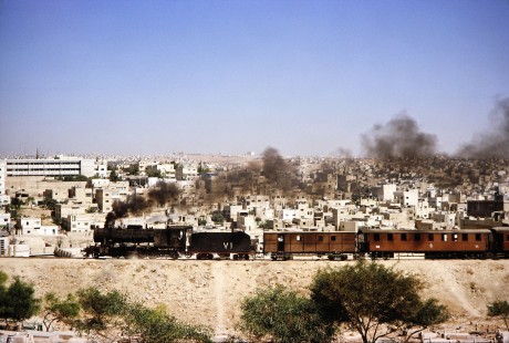 Hedjaz Jordan Railway 2-8-2 steam locomotive no. 71 travels alongside the city scape in Amman, Jordan, on July 15, 1991. Photograph by Fred M. Springer, © 2014, Center for Railroad Photography and Art. Springer-Hedjaz-ZimZam(1)-02-24