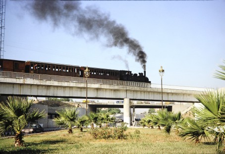 Syrian Railways 2-6-0 steam locomotive no. 130-751 moves on a bridge across a busy highway in Damascus, Syria on July 20, 1991. Photograph by Fred M. Springer, © 2014, Center for Railroad Photography and Art. Springer-Hedjaz-ZimZam(1)-09-24