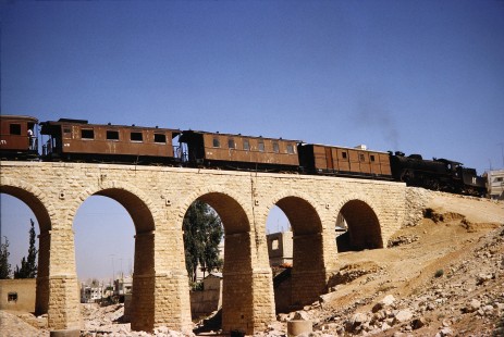 Hedjaz Jordan Railway 4-6-2 steam locomotive no. 82 crossing a bridge while pulling passenger cars in Amman, Jordan, on July 16, 1991. Photograph by Fred M. Springer, © 2014, Center for Railroad Photography and Art. Springer-Hedjaz-ZimZam(1)-04-33
