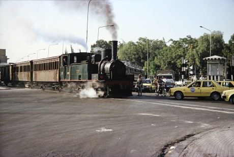 Syrian Railways 2-6-0 steam locomotive no. 130-751 crosses a busy intersection of cars in Damascus, Syria on July 20, 1991. Photograph by Fred M. Springer, © 2014, Center for Railroad Photography and Art. Springer-Hedjaz-ZimZam(1)-09-27