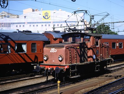 Swedish State Railways electric service locomotive no. 283 moves along a row of passenger cars with the station in the background in Gothenburg, Västra Götaland, Norway, on June 11, 1989. Photograph by Fred M. Springer, © 2014, Center for Railroad Photography and Art. Springer-Scan-Swiss-York-10-06