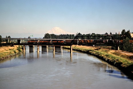 Northbound Milwaukee Road freight train crossing Puyallup River at Tacoma, Washington, with Mt. Ranier in background on July 15, 1979. Photograph by John F. Bjorklund, © 2016, Center for Railroad Photography and Art. Bjorklund-68-13-03