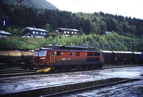 Norwegian State Railways electric locomotive no. 14-2167 moves along the platform in Dombås, Oppland, Norway on June 8, 1989. This photograph is taken as the photographer travels the areas of Nordland and Sør-Trøndelag, Norway. Photograph by Fred M. Springer, © 2014, Center for Railroad Photography and Art. Springer-Scan-Swiss-York-08-07