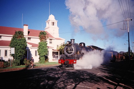 South African Railway 4-8-2 steam locomotive no. 2649 or "Anna" moves into a town alongside a young biker in Fauresmith, Free State, South Africa, on March 31, 1995. Photograph by Fred M. Springer, © 2014, Center for Railroad Photography and Art. Springer-So.Africa-NOR-SWE-02-15