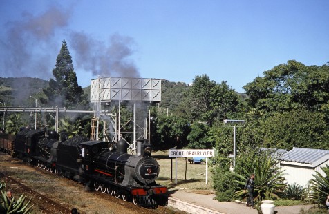 South African Railway steam locomotives no. 1007 and no. 1056 approach Great Brak River train stop and Groot Brakrivier in  Great Brak River, Western Cape, South Africa, on March 21, 1995. Photograph by Fred M. Springer, © 2014, Center for Railroad Photography and Art. Springer-So.Africa(1)-14-30