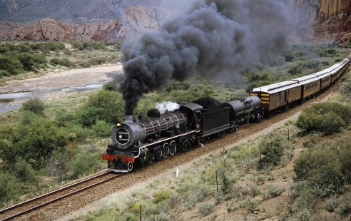 South African Railway 4-8-2 steam locomotive no. 1882 travels by the Red Mountain in Calitzdorp, Western Cape, South Africa, on March 24, 1995. Photograph by Fred M. Springer, © 2014, Center for Railroad Photography and Art. Springer-So.Africa(1)-17-14