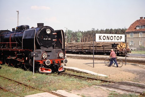Polskie Koleje Państwowe (Polish State Railways) steam locomotive no. Pt47-65 waits at Konotop station as a man with a bike walks by and a load of logs resides on a nearby track in Konotop, Greater Poland, Poland, on May 20, 1993. Photograph by Fred M. Springer, © 2014, Center for Railroad Photography and Art. Springer-Europe-03-39