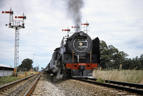 Low-angle view of oncoming South African Railway 4-8-4 steam locomotive no. 3410 or "Paula" passing semaphore signals in Marseilles, Free State, South Africa, on March 26, 1995. Photograph by Fred M. Springer, © 2014, Center for Railroad Photography and Art. Springer-So.Africa(1)-21-36