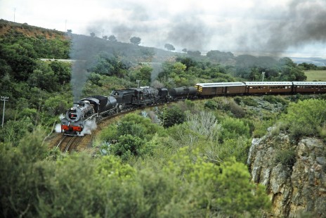 South African Railway steam locomotives no. 2683 and no. 4122 pass along a curved track near a bluff in Gouritz, Western Cape, South Africa, on March 20, 1995. Photograph by Fred M. Springer, © 2014, Center for Railroad Photography and Art. Springer-So.Africa(1)-11-08
