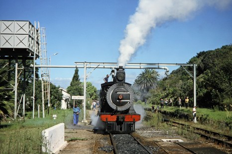 South African Railway steam locomotives no. 1007 and no. 1056 wait at the cross roads at Groot Brakrivier with many onlookers in Great Brak River, Western Cape, South Africa, on March 31, 1995. Photograph by Fred M. Springer, © 2014, Center for Railroad Photography and Art. Springer-So.Africa(1)-13-34