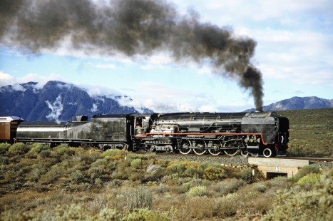 South African Railway 4-8-4 steam locomotive no. 3501 speeds over a small bridge against the hills in Western Cape, South Africa, on March 19, 1995. Photograph by Fred M. Springer, © 2014, Center for Railroad Photography and Art. Springer-So.Africa(1)-10-10