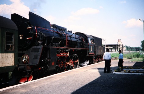 Polskie Koleje Państwowe (Polish State Railways) steam locomotive no. 0l49-105 travels past two railroad workers talking on the platform in Powodowo, Greater Poland, Poland, On May 21, 1993. Photograph by Fred M. Springer, © 2014, Center for Railroad Photography and Art. Springer-Europe-04-33