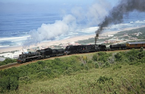 High view above the Indian Ocean for South African Railway steam locomotives nos. 2683 and 4122 in Western Cape, South Africa, on March 22, 1995. Photograph by Fred M. Springer, © 2014, Center for Railroad Photography and Art. Springer-So.Africa(1)-14-12