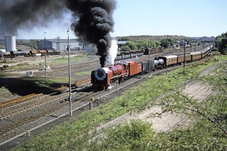 South African Railway 4-8-4 steam locomotive no. 3417 travels between an empty road and the nearby train yard in  De Aar, Northern Cape, South Africa, on April 1, 1995. Photograph by Fred M. Springer, © 2014, Center for Railroad Photography and Art. Springer-So.Africa-NOR-SWE-04-21