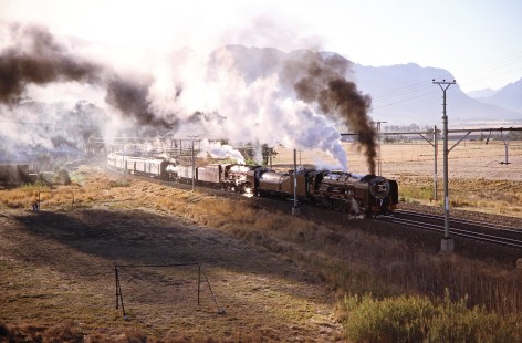 South African Railway 4-8-4 steam locomotives nos. 3417 and 3501 travel next to a local soccer field near twilight in Artois, Western Cape, South Africa, on April 2, 1995. Photograph by Fred M. Springer, © 2014, Center for Railroad Photography and Art. Springer-So.Africa-NOR-SWE-06-24