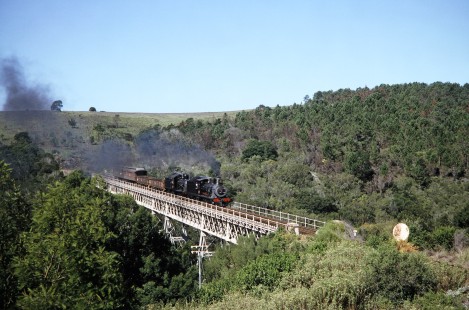 South African Railway steam locomotives no. 1007 and no. 1056  move across the Malgaaten bridge in Western Cape, South Africa, on March 21, 1995. Photograph by Fred M. Springer, © 2014, Center for Railroad Photography and Art. Springer-So.Africa(1)-14-33