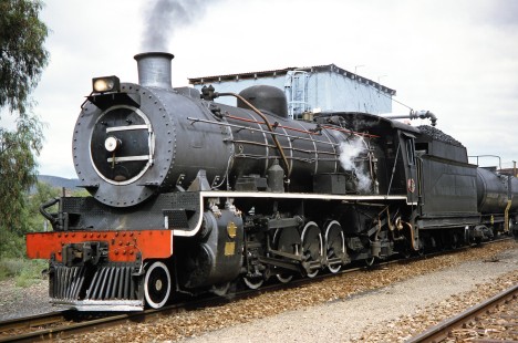South African Railway 4-8-2 steam locomotive no. 1882 by a water tank in Oudtshoorn, Western Cape, South Africa, on March 24, 1995. Photograph by Fred M. Springer, © 2014, Center for Railroad Photography and Art. Springer-So.Africa(1)-17-22