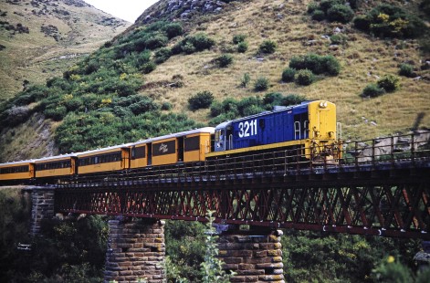 Taieri Gorge Railway diesel locomotive no. 3211 pulls a passenger train onto a bridge in Dunedin, Otago, New Zealand, on January 19, 1994. Photograph by Fred M. Springer, © 2014, Center for Railroad Photography and Art. Springer-NZ(1)-16-21
