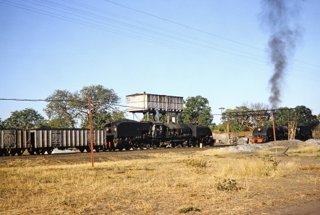 Two National Railways of Zimbabwe steam locomotives meet as workers talk with one another in Hwange, Matabeleland, Zimbabwe, on August 5, 1991. Photograph by Fred M. Springer, © 2014, Center for Railroad Photography and Art. Springer-Hedjaz-ZimZam(1)-22-35