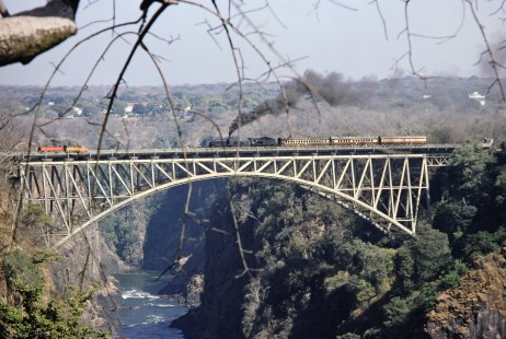 A Garratt steam locomotive leads a three-car passenger train over the Victoria Falls Bridge between Livingstone, Zambia, and Victoria Falls Zimbabwe, on August 7, 1991. Photograph by Fred M. Springer, © 2014, Center for Railroad Photography and Art. Springer-ZimZam(2)-Swiss-19-08